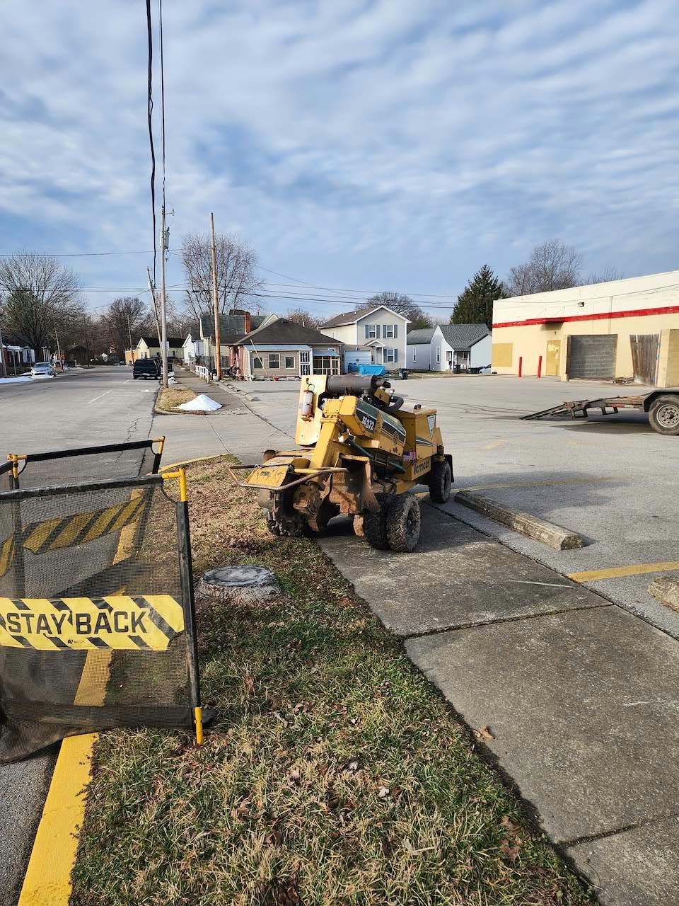 Stump grinder set up on a commercial street with safety barriers